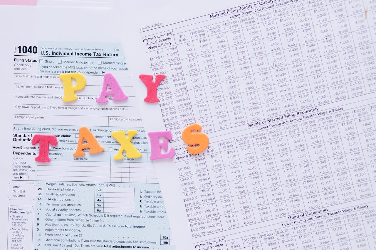 Close-up of U.S. tax forms with colorful PAY TAXES letters emphasizing financial deadlines.